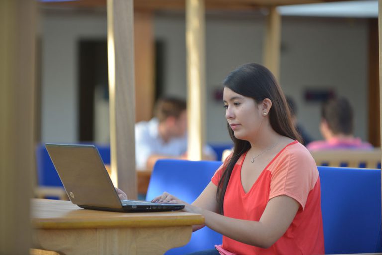 Alumna de iU tomando clases virtuales en su laptop