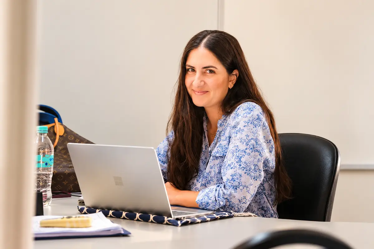 Asesora académica de iU sonriendo frente a su computadora